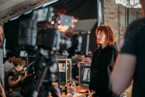 The director is a woman at work on the set. The director works with a group or with playback during the filming of a movie  commercial or TV series. Film crew  equipment and group. 