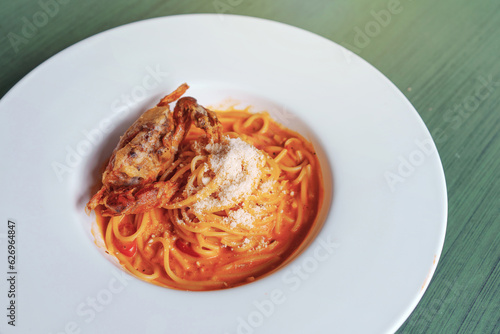 Deep Fried Soft Shell Crab Spaghetti with Tomato Sauce sprinkle with cheese in a white plate.
