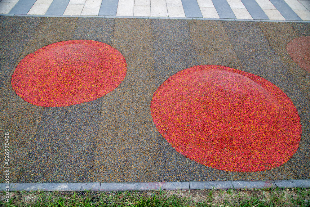 Children's mounds covered with rubberized pink and gray coating on the playground on a clear sunny day. Sports Recreation Entertainment. Children's mounds covered with rubberized pink and gray coating on the playground on a clear sunny day. Sports Recreation Entertainment.