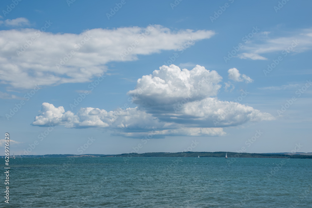 fluffy white clouds in the summer against a blue sky in the shape of a bird of prey over the sea