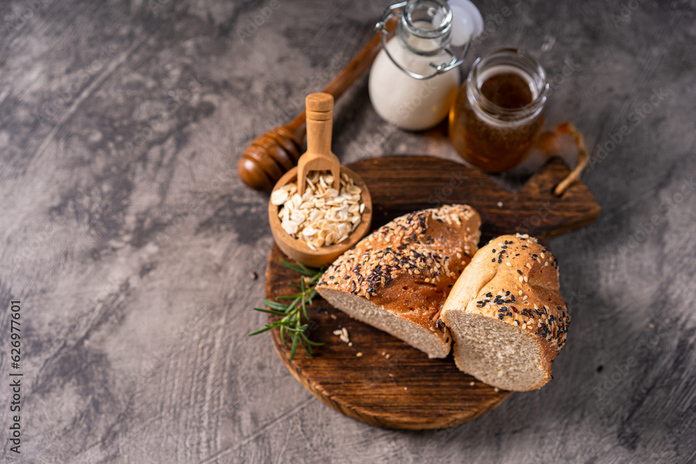 Artisan bread whole wheat baguette white milk and honey on rustic wooden board and abstract table. Sourdough bread
