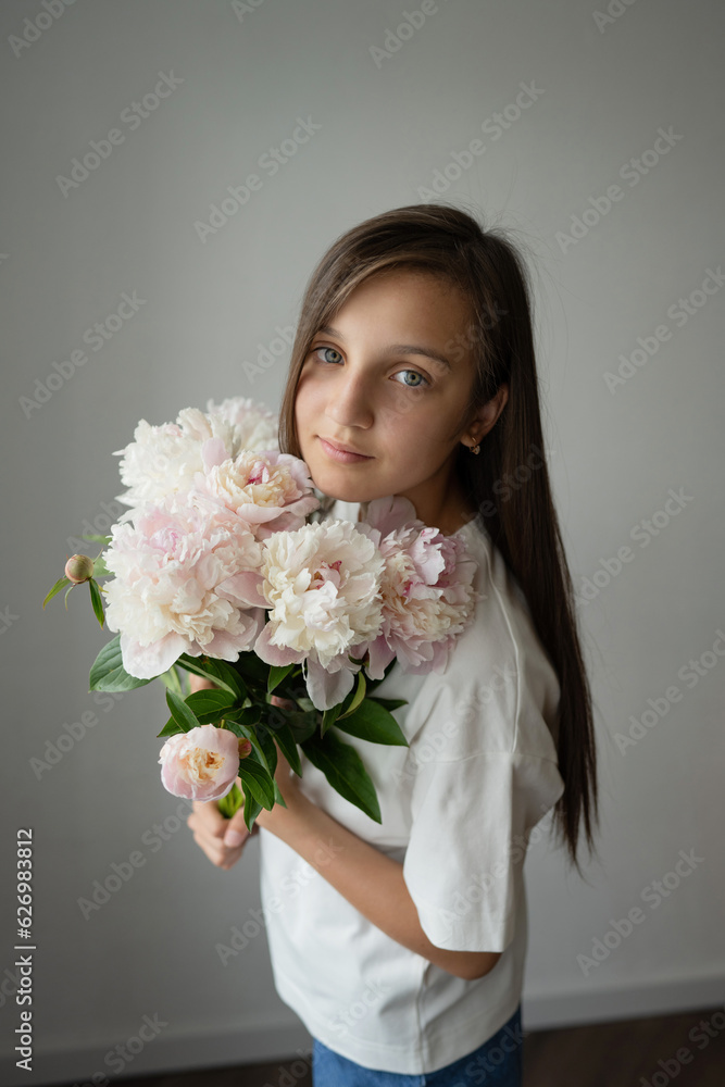 Calm preteen girl child standing with blooming peony flower with stem Calm preteen girl child standing with blooming peony flower with stem