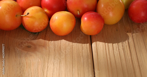 Red cherry plum on a wooden table with empty space. fresh fruits on a sunny day. veggie food. High quality photo.
