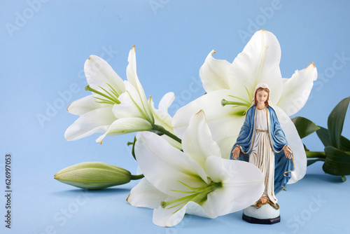 Assumption of Mary day. Virgin Mary figurine with lily flowers. photo