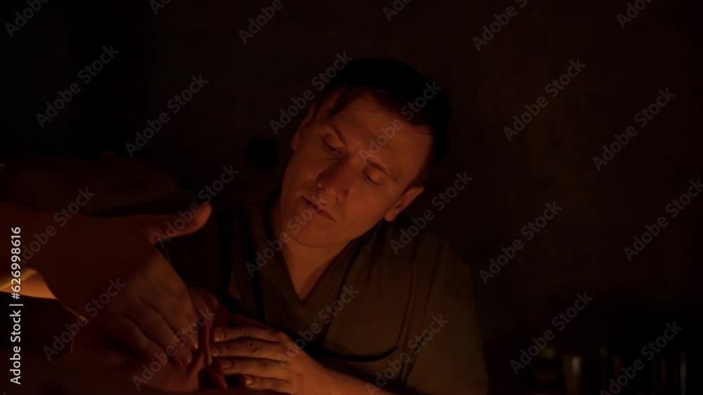 The masseur gives a facial massage. Candlelit atmosphere, contrasting scene, slow motion. An attentive massage therapist works in his office. The masseur gives a facial massage. Candlelit atmosphere, contrasting scene, slow motion. An attentive massage therapist works in his office.