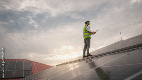 A service engineer checks a solar cell that is mounted on the roof to see if there is a damaged component that needs to be repaired. Concept of energy from natural sources.