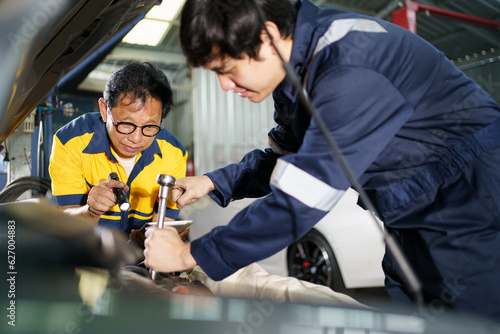 Team of vehicle technicians checking and measuring a vehicle oil engine or engine lubricant level by using oil stick indicator. Senior professional repairman inspecting an oil engine in an old car.