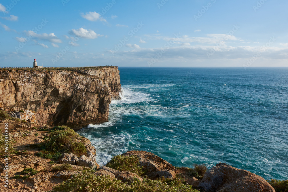 Farol de Sagres on the edge of the cliff washed by the big ocean waves. The lighthouse in Sagres Fortress, Portugal