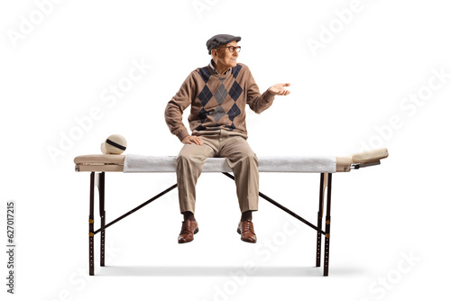 Elderly man sitting at a physical therapy bed and gesturing with hand