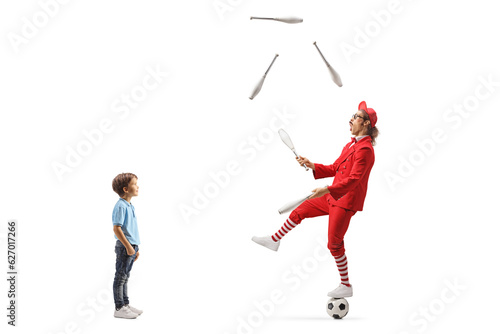 Boy watching a man in a red suit standing on a football and juggling