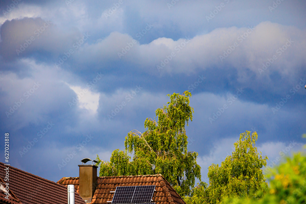 Dark storm clouds pile up over the roof of a residential building with photovoltaic modules Dark storm clouds pile up over the roof of a residential building with photovoltaic modules