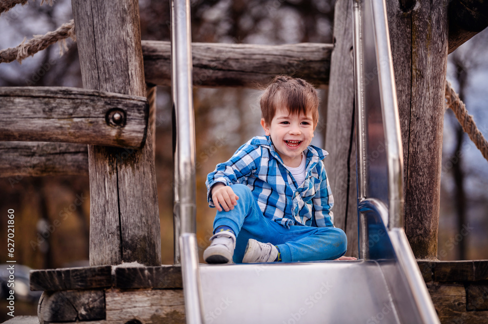 Little toddler boy in blue shirt trying to climb down a wooden ladder on playground Little toddler boy in blue shirt trying to climb down a wooden ladder on playground
