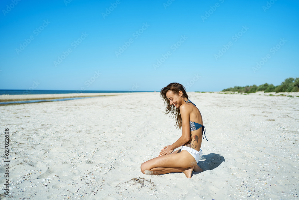 Joyful latin girl sitting on white sand at serene secluded seashore. This delightful moment joy and freedom of a beachside vacation on a serenity island