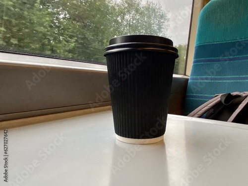 Disposable blank Cup of coffee is on the table in the train. Big window, Traveling alone