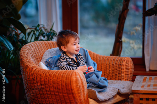 Little toddler boy having rest covered himself in blue pleid in straw chair photo