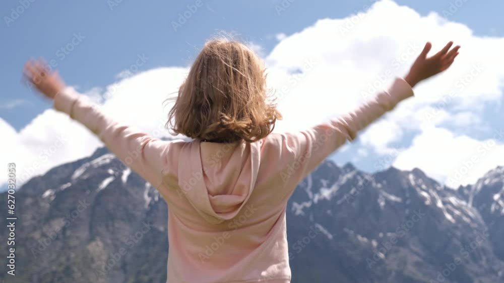 Rear view of child waving hands in mountains, little girl raising her arms in highlands, enjoying amazing view Rear view of child waving hands in mountains, little girl raising her arms in highlands, enjoying amazing view