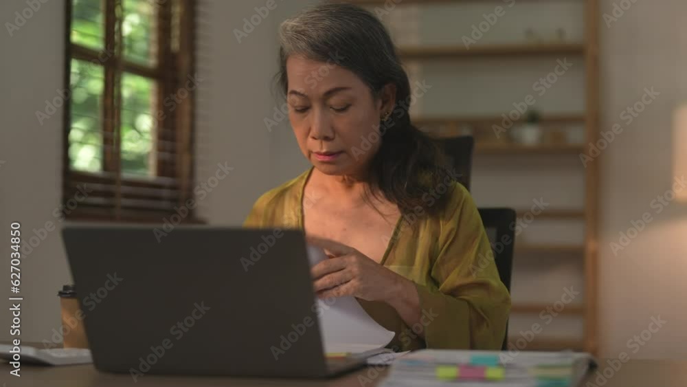 Asian female senior entrepreneur using her laptop at home. Asian female senior entrepreneur using her laptop at home.