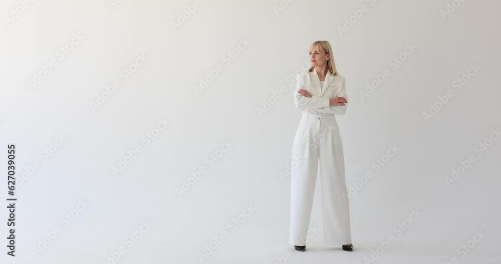 Confident and businesslike woman dressed in formal attire, standing against a pristine white backdrop. She glances thoughtfully to the side, projecting an air of contemplation and determination. Confident and businesslike woman dressed in formal attire, standing against a pristine white backdrop. She glances thoughtfully to the side, projecting an air of contemplation and determination.