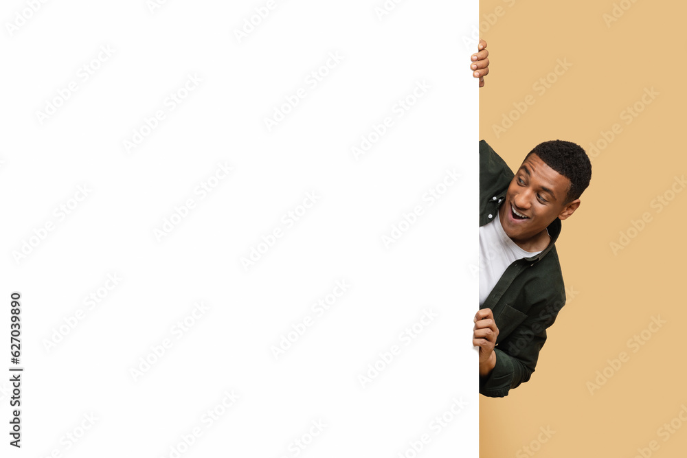Excited young black guy looking at white blank advertising board Excited young black guy looking at white blank advertising board