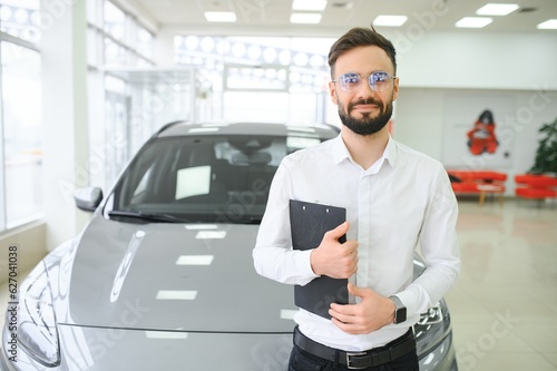 Confident young caucasian businessman shop assistant standing in car automobile dealer shop © Serhii