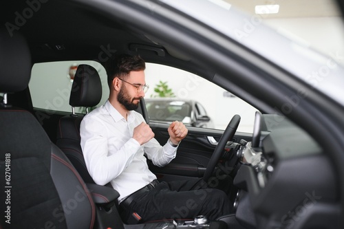 a man examines a car in a car dealership © Serhii