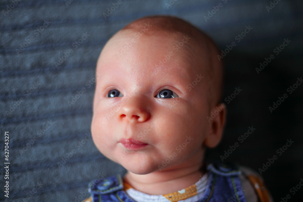 A little boy, newborn, with beautiful blue eyes looks into the distance A little boy, newborn, with beautiful blue eyes looks into the distance