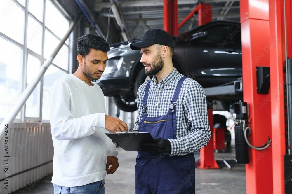 A mechanic in a car service is talking to an Indian car owner. Car service concept.