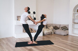 Sporty couple practicing yoga in spacious living room