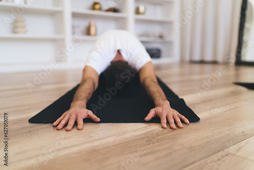 Anonymous man sitting in yoga pose on floor