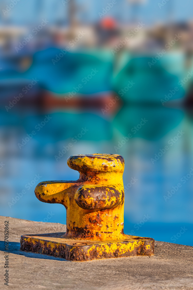 Vertical shot of a rustic yellow bitts single bollards at the Hout Bay harbour, Cape Town, South Africa Vertical shot of a rustic yellow bitts single bollards at the Hout Bay harbour, Cape Town, South Africa