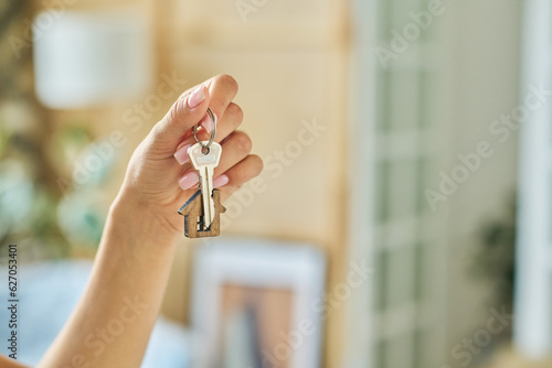 Obraz na plátně Hand of young woman holding metallic key with house shaped trinket hanging on ri