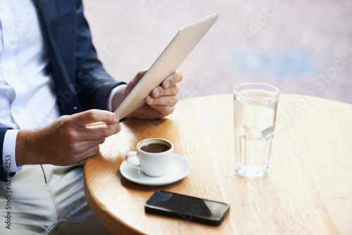 Online from anywhere he goes. Cropped view of a businessman using his digital tablet in a cafe while he waits.