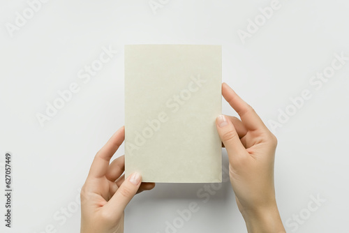 female hands holding a blank postcard on a gray background