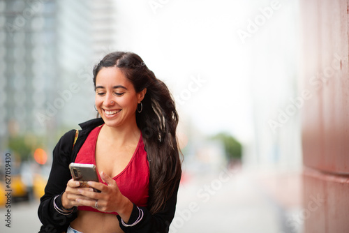 young smiling woman looking at mobile phone in city Free Download young smiling woman looking at mobile phone in city - GFXLoad
