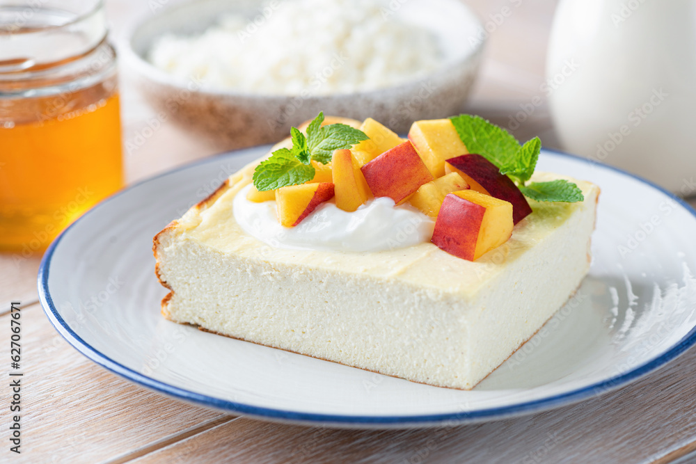 Sweet cottage cheese casserole, zapekanka served with fresh peach and mango cubes, closeup view