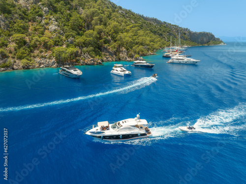 Aerial view of beautiful yachts and boats on the sea at summer sunny day. Fethiye lagoons, Turkey. Top view of bay, luxury yachts, sailboats, clear blue water, beach, mountain and green forest. Travel © den-belitsky