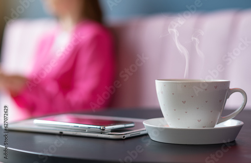 A refreshing cup of hot coffee in a cafe on the background of a freelancer girl