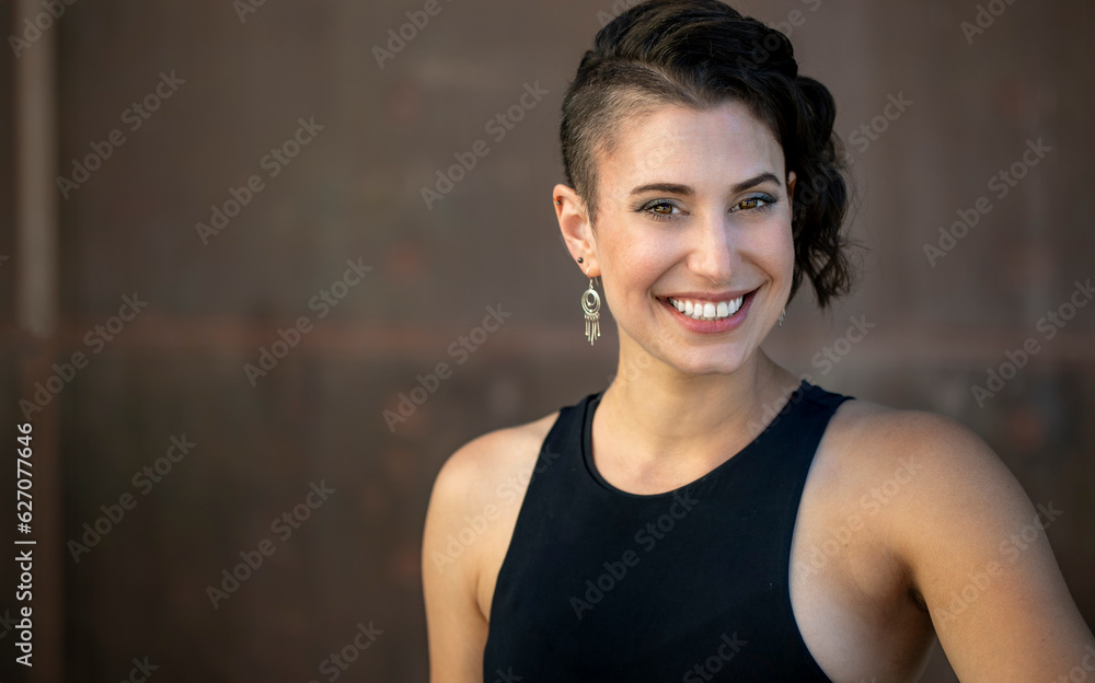 A lifestyle head shot of a very charismatic lively, positive, cheerful, unique woman with a stylish haircut