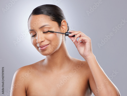 Brush, mascara and woman in studio for makeup, cosmetics and results on grey background. Eyelash, curling and face of Indian female model with beauty tool for treatment, application or volume