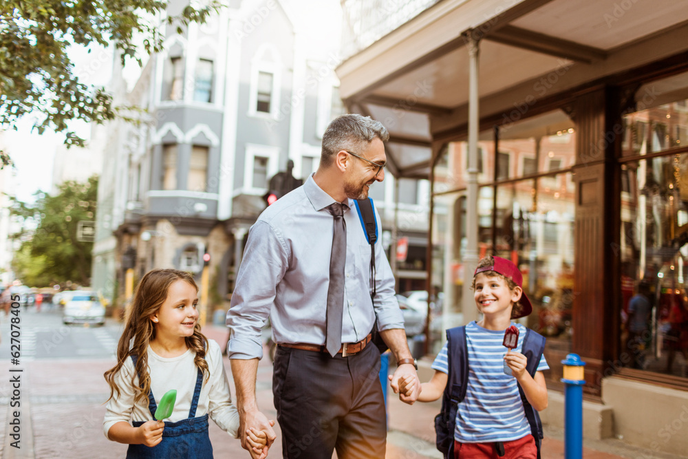 Father taking his kids home from school in the city downtown Father taking his kids home from school in the city downtown