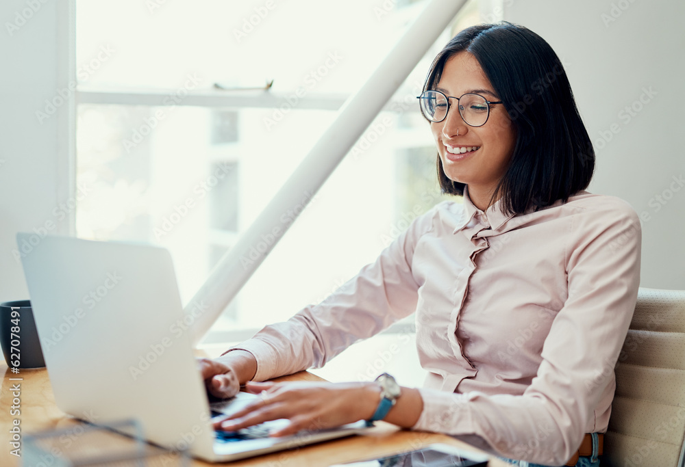 Working through my day with a smile. Cropped shot of an attractive young businesswoman sitting alone and using her laptop in the office. Working through my day with a smile. Cropped shot of an attractive young businesswoman sitting alone and using her laptop in the office.