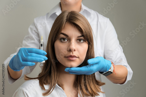 Portrait of a young girl and hands of a beautician with a syringe  cosmetic injections.