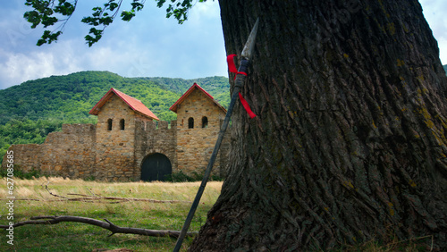 Roman fort and a spear leaning on an old tree in a summer day. photo