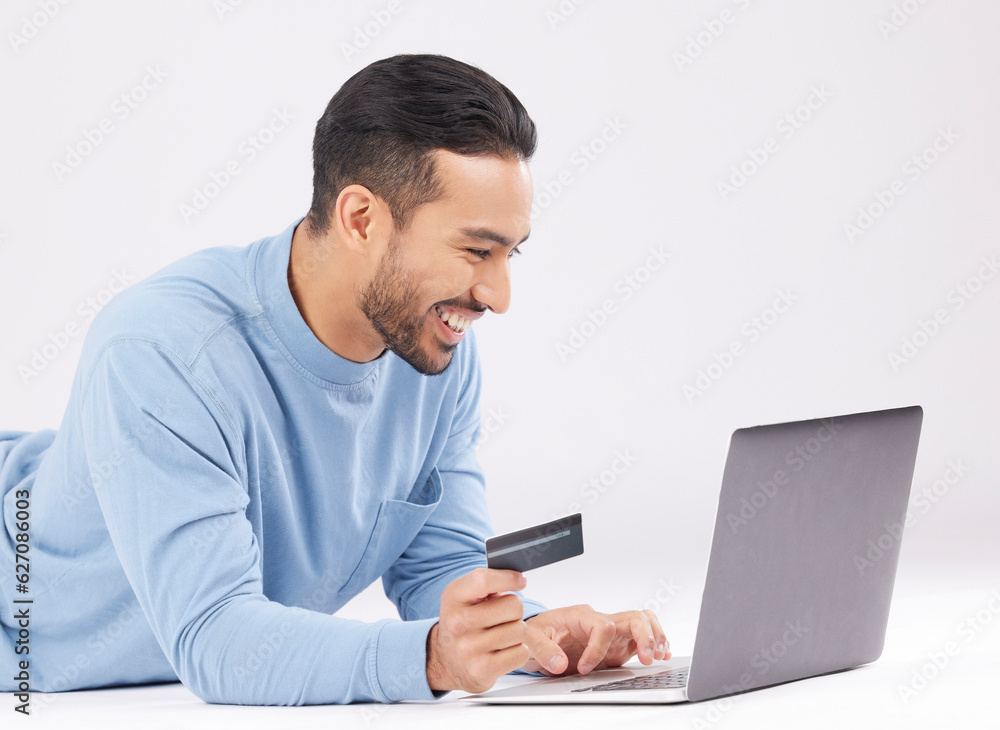 Laptop, credit card and happy asian man on studio floor for ecommerce, sale or cashback on grey background. Online shopping, deal and Japanese male customer smile for loan, payment or sign up promo Laptop, credit card and happy asian man on studio floor for ecommerce, sale or cashback on grey background. Online shopping, deal and Japanese male customer smile for loan, payment or sign up promo