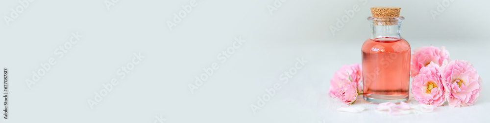 Concept of perfume with pure natural organic rose ingredient, essential oils. Glass bottles with flower herbal extract and elixir. Perfumery cosmetic toilet water fragrance, banner copy space for text Concept of perfume with pure natural organic rose ingredient, essential oils. Glass bottles with flower herbal extract and elixir. Perfumery cosmetic toilet water fragrance, banner copy space for text