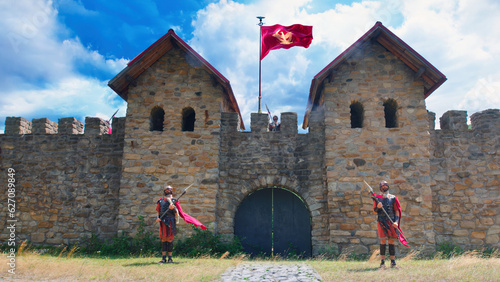 Roman soldiers guarding a military fort on a cloudy summer day. The flag of the Roman Empire fluttering on the crenellated wall between the watchtowers. photo
