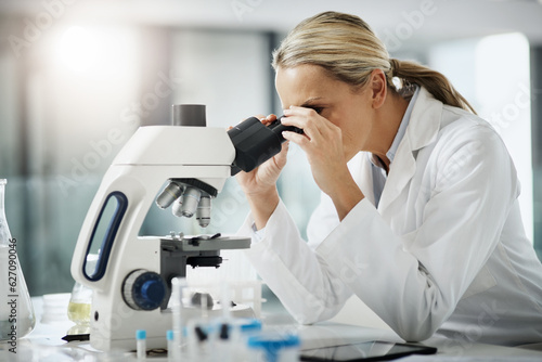 Taking a closer look. Cropped shot of an attractive mature female scientist using a microscope while doing research in her lab.