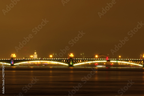 Night view of the bridge over the river illuminated by light, blurry. Night shot through the fog. © Alex Chebak