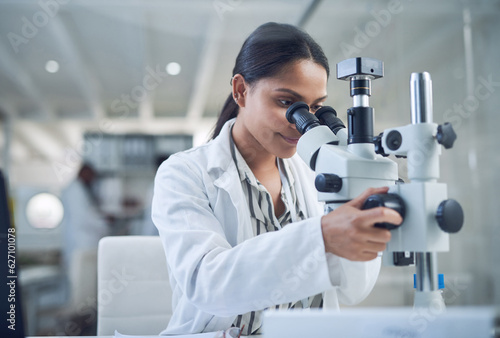 Science, microscope and innovation with a woman in a laboratory for medical research or experiment. Healthcare, medicine and a young indian engineer working in a lab for pharmaceutical development