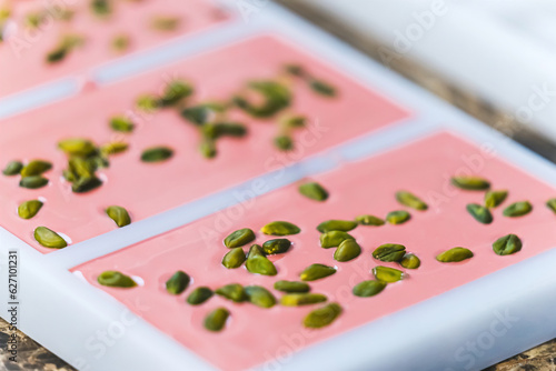 Closeup shot of handmade ruby chocolate with pistachios. Delicious ruby chocolate in bar moulds. Chocolate manufacture concept. High quality photo